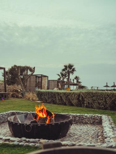 a fire pit in a park with the ocean in the background at BABERRIH Hôtel Hospitality Palaces & Resorts in Essaouira
