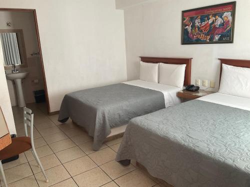 a hotel room with two beds and a table at Hotel Camba in Oaxaca City