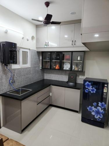 a kitchen with white cabinets and blue flowers on the counter at Modern New 2 BHK Studios in Kondapur Near Gachibowli in Hyderabad