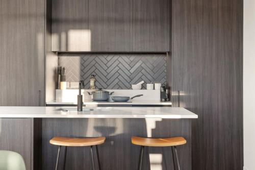 a kitchen with two bar stools and a sink at ParkHaven - Views, Luxury and central -By KOSH BNB in Hamilton