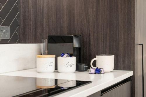 three coffee mugs sitting on a counter in a kitchen at ParkHaven - Views, Luxury and central -By KOSH BNB in Hamilton