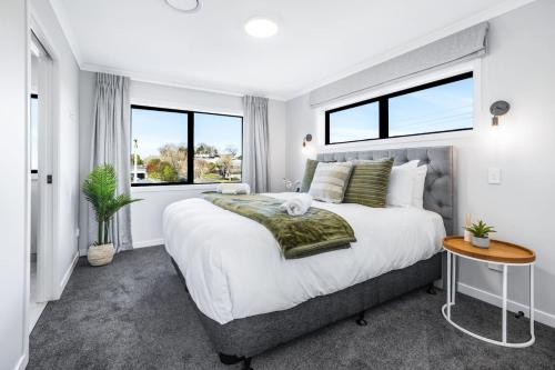 a bedroom with a large bed and two windows at Luxury, Modern with King Bed and Views- By KOSH BNB in Hamilton