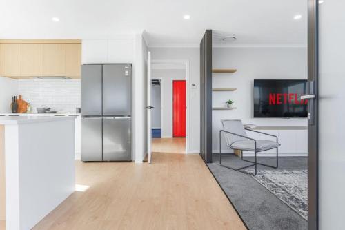 a kitchen with a refrigerator and a table with a chair at Luxury, Modern with King Bed and Views- By KOSH BNB in Hamilton