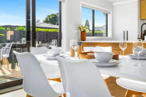 a white dining room with a white table and white chairs at Luxury, Modern with King Bed and Views- By KOSH BNB in Hamilton