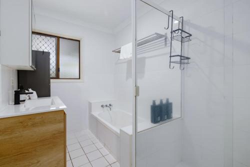 a white bathroom with a tub and a sink at Best Value 4Beds Home Near Shops, Cafes and Forest in Brisbane
