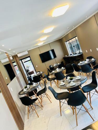 a conference room with tables and chairs and a flat screen tv at Hotel Aris in União da Vitória