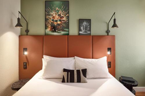 a bedroom with a large bed with white pillows at IBIS Port de plaisance in Caen