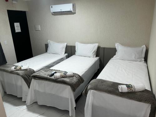 three beds in a hospital room with white sheets at Hotel Aris in União da Vitória