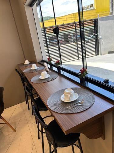 a long wooden table with chairs and a large window at Hotel Aris in União da Vitória