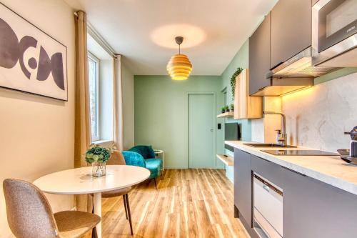 - une cuisine avec une table, une petite table et des chaises dans l'établissement Le Cèdre Bleu - Bel appart climatisé quartier point du jour Lyon 5, à Lyon