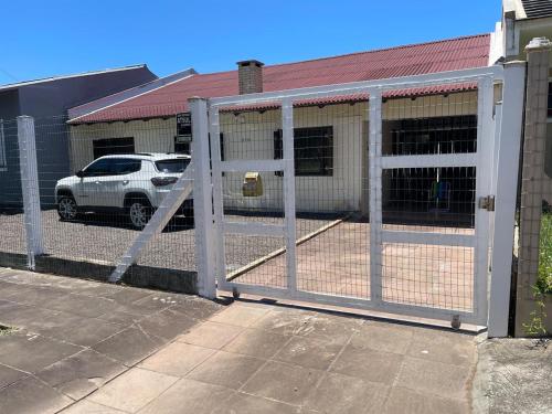 a fence with a gate in front of a parking lot at Casa da Praia in Osório