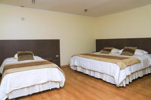 two beds in a room with wooden floors at Vitrali Suite in Copiapó