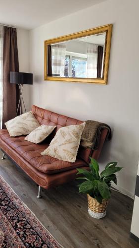 a brown leather couch in a living room with a mirror at Mia Casa in Kehl am Rhein