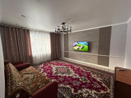 un soggiorno con una televisione e un grande tappeto di Privat House a Karakol