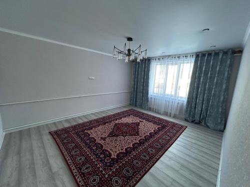 una stanza vuota con un tappeto rosso sul pavimento di Privat House a Karakol