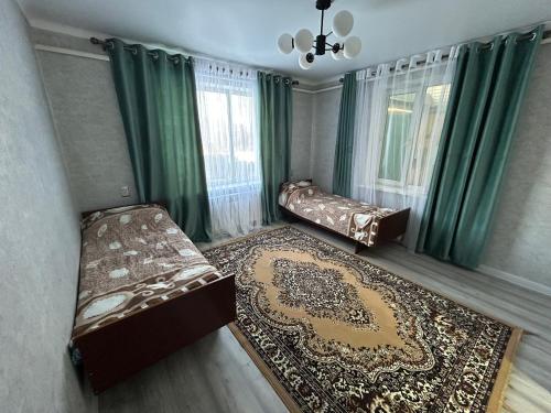 una camera da letto con due letti e un tappeto di Privat House a Karakol