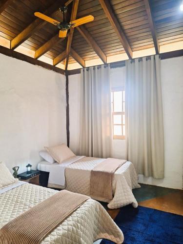 a bedroom with two beds and a ceiling fan at Pousada Mãe Terra in Torrinha