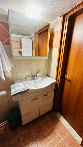 a bathroom with a sink and a wooden door at KSD apartment in Kallithea Halkidikis