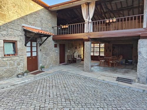 a stone house with a balcony and a patio at Casa do Muro Alto in Alvelos