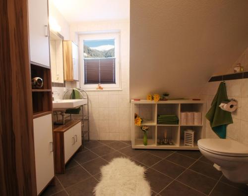 uma casa de banho com um lavatório, um WC e uma janela. em Appartement Edelweiss mit Infrarotkabine em Großsölk