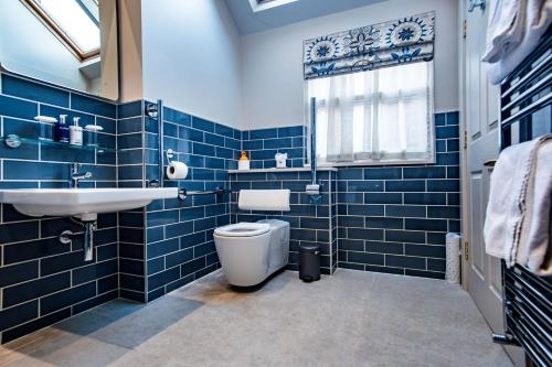 a blue tiled bathroom with a toilet and a sink at Hotel Victoria in Whitby