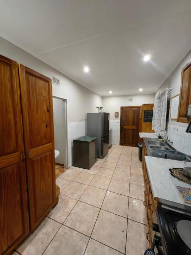 a kitchen with wooden cabinets and a tiled floor at Kudus Hide in Richards Bay