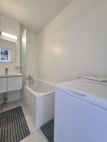 une salle de bain blanche avec une baignoire et un lavabo dans l'établissement Chez Laurette, à Balaruc-les-Bains