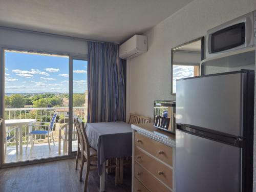 a kitchen with a refrigerator and a table and a balcony at Chez Laurette in Balaruc-les-Bains