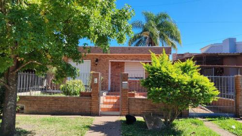a brick house with a gate and a fence at Cálida y Familiar in Salto