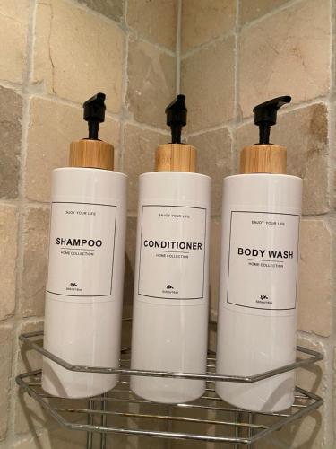 three shampoo and conditioner bottles sitting on a shelf at Villa Thorse in Husvik