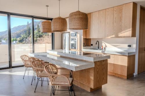 a kitchen with a large counter with chairs and windows at Casa Ambar Villa in San Juan Cosalá