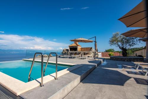 a swimming pool with a gazebo next to the water at Villa Zgodić in Lovran