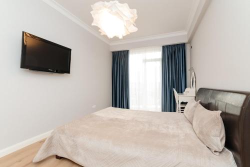 a bedroom with a bed and a flat screen tv at City Walk Apartment & MiRent in Chişinău