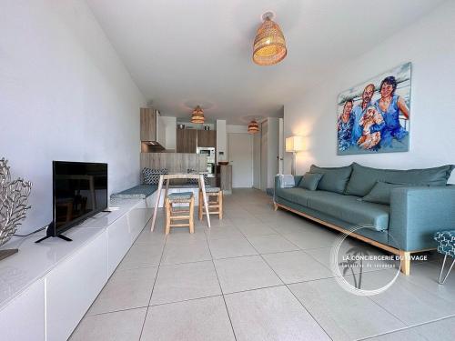 un salon avec un canapé bleu et une cuisine dans l'établissement Le Rivage - À 50m de la plage des Salins - Piscine, à Hyères