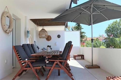 une table et des chaises avec un parasol sur une terrasse dans l'établissement Le Rivage - À 50m de la plage des Salins - Piscine, à Hyères
