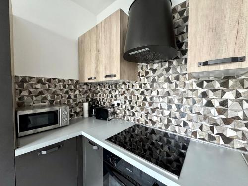 a kitchen with a microwave and a black hood at Steps from Three Cities 2BR Apt in Il-Wileġ