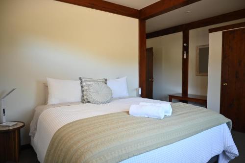 a bedroom with a large bed with white sheets at Muirs Reef Lodge Kinloch holiday home Lake Taupo in Kinloch