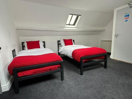 two beds in a room with red pillows at St James's Terrace Studio Rooms in Nottingham
