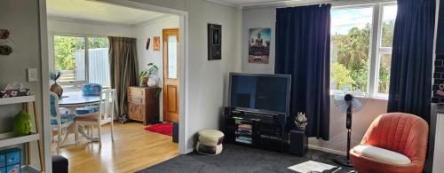 a living room with a television and a desk at Marg's on the Corner in Kumara