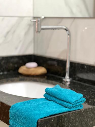 two blue towels sitting on a counter next to a sink at Casa Mazaratto - Hospedagem in Manhã