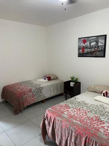 a bedroom with two beds and a picture on the wall at Casa Puerta Paraíso in Tepic
