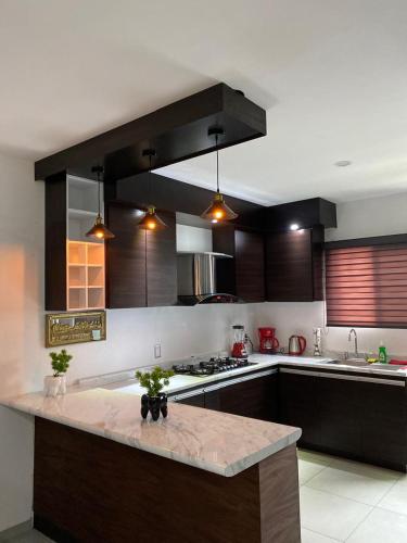 a kitchen with wooden cabinets and a counter top at Casa Puerta Paraíso in Tepic