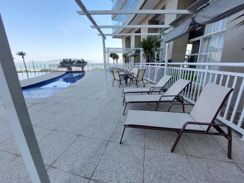 a group of chairs sitting on a balcony with the ocean at Book Santos - Unlimited 1608 Panorâmico c/ 3 dorm in Santos