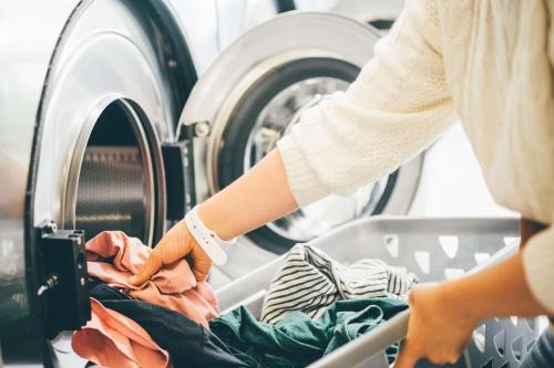 a woman putting clothes into a washing machine at Comfort Hotel ERA Kobe Sannomiya in Kobe