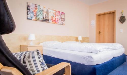 a bedroom with a large bed and a chair at Hotel Zum Grunewald in Dinslaken
