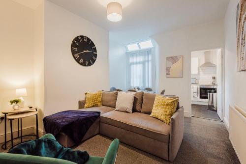 a living room with a couch and a clock on the wall at Free parking, late check out CoOp Live Etihad Stadium 3-bed house in Manchester
