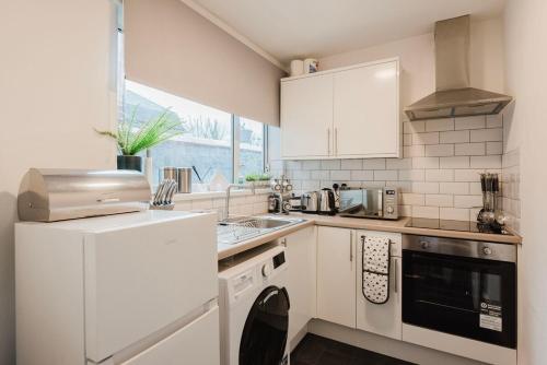 a white kitchen with a sink and a microwave at Free parking, late check out CoOp Live Etihad Stadium 3-bed house in Manchester