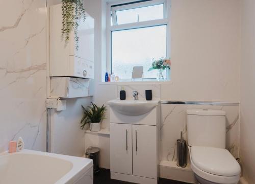 a bathroom with a sink and a toilet and a window at Free parking, late check out CoOp Live Etihad Stadium 3-bed house in Manchester