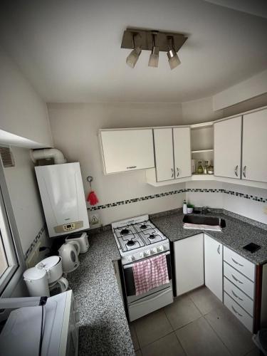 a kitchen with white cabinets and a stove top oven at Alsina - Central Point Apartments in Salta
