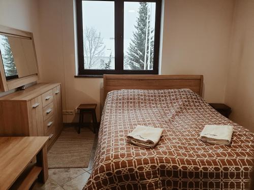 a bedroom with a bed with two towels on it at Go2Krynica - Zielony PitStop in Krynica Zdrój